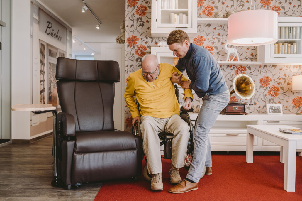 Der 1. Beitrag, welchen wir für die Swiss Handicap 2022 veröffentlicht haben. Auf dem Bild ist ein älterer Mann in einem Pflegesessel zu sehen, welcher von einem Pfleger liebevoll in den Sessel transferiert wird.
